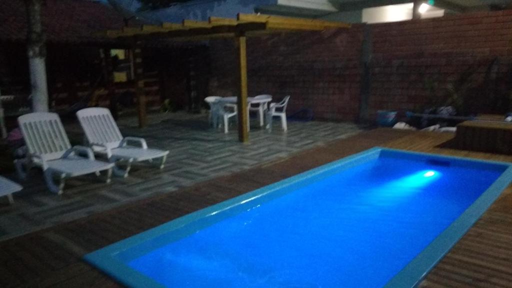 una piscina azul con sillas y una mesa en Casa em bombinhas - sc, en Bombinhas