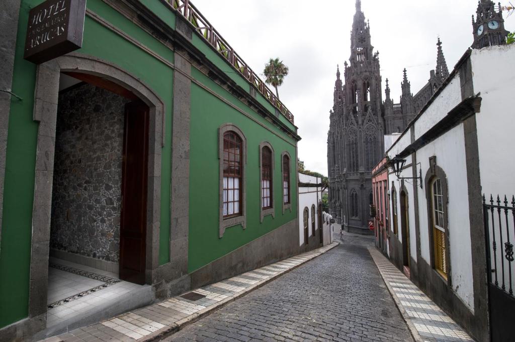 an alley with a green building and a church at Hotel Emblemático Arucas in Arucas