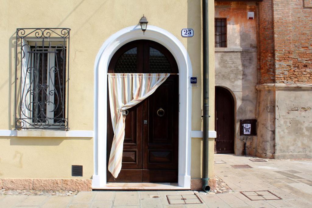 uma porta castanha com uma cortina branca num edifício em Porta del Carmine em Comacchio