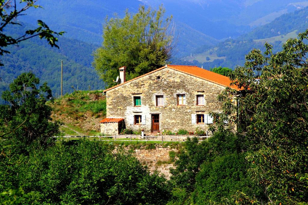 una antigua casa de piedra con techo naranja en una colina en Mas Taillet Maison de Xatart, en Prats-de-Mollo-la-Preste