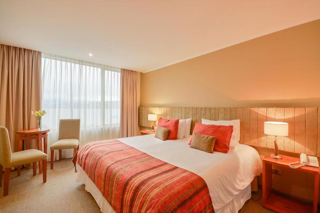 una habitación de hotel con una cama grande y una silla en Hotel Terraza Suite, en Villarrica