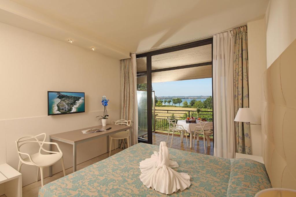 a bedroom with a bed and a desk and a balcony at Hotel Holiday in Sirmione