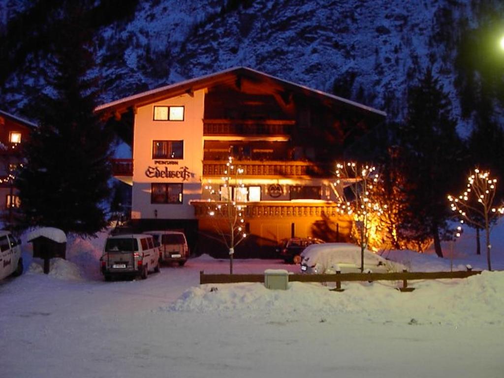 un grand bâtiment avec des lumières de Noël dans la neige dans l'établissement Pension und Apartment Edelweiß, à Heiligenblut