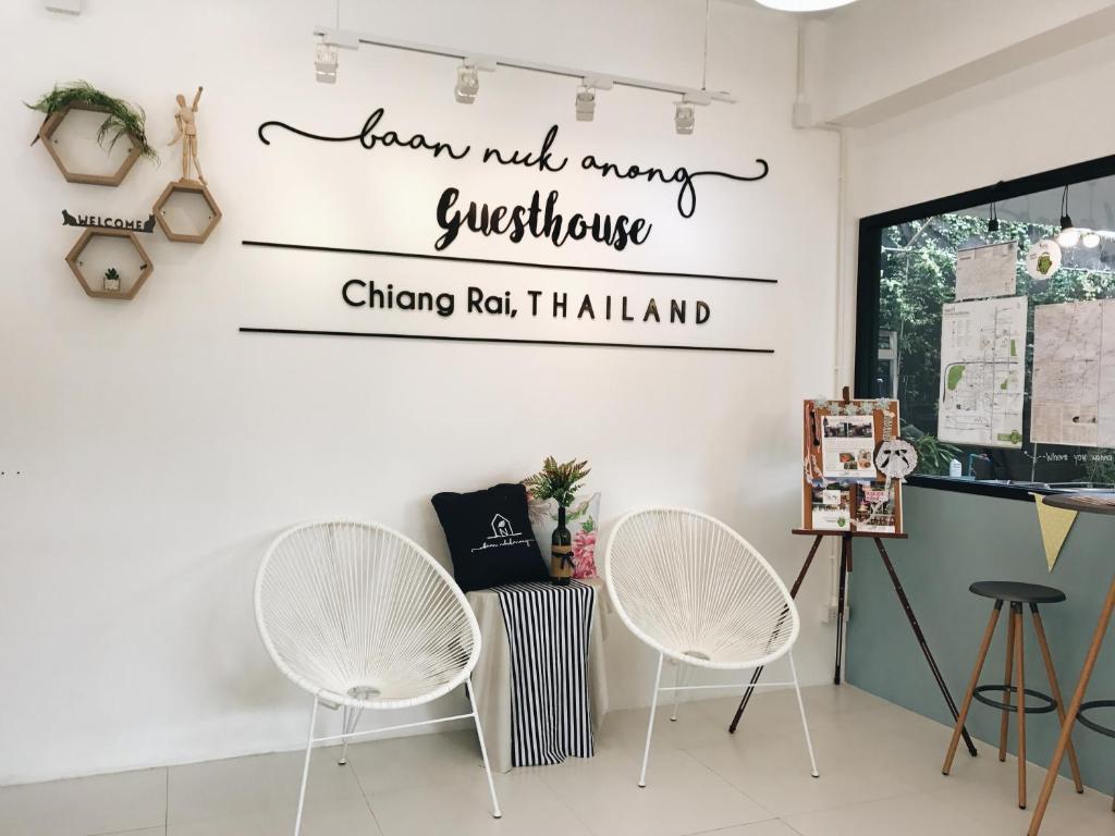 una stanza con due sedie e un cartello che dice "impara non molte domande Chicago" di Baan Nukanong Guesthouse a Chiang Rai