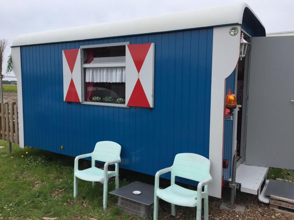 a blue and white trailer with two chairs and a window at B&B boerderij rust, in pipowagens! in Den Helder