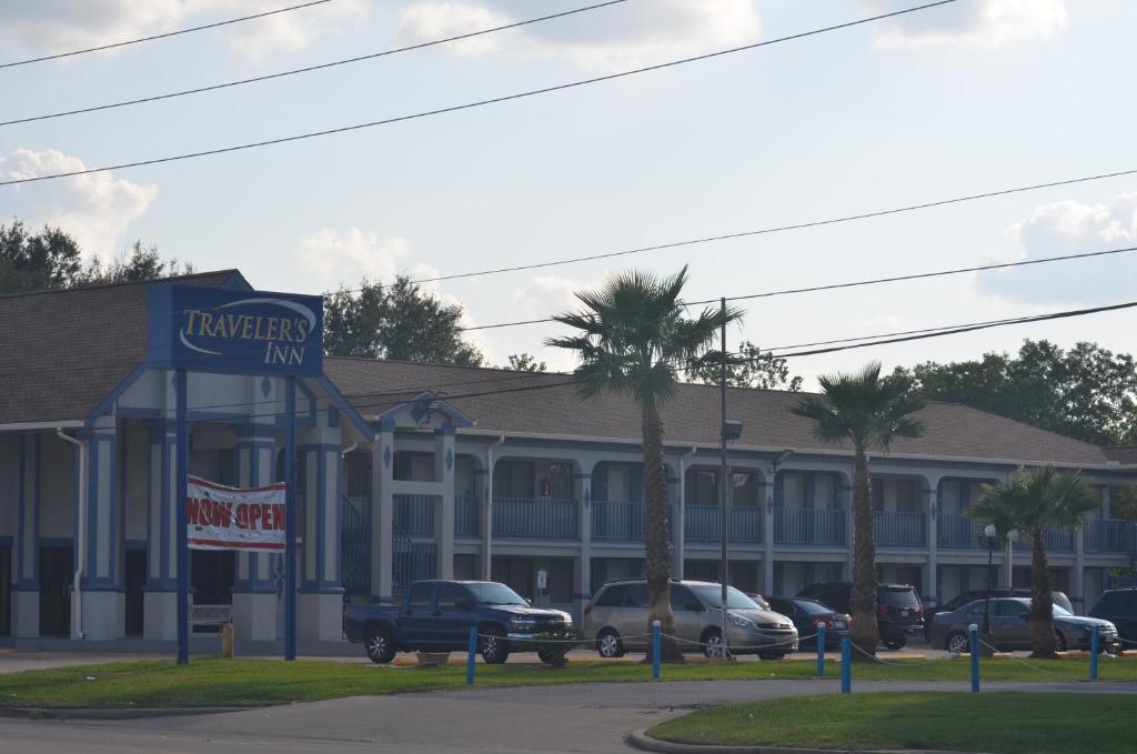 a hotel with cars parked in front of a building at Travelers Inn in Rosenberg