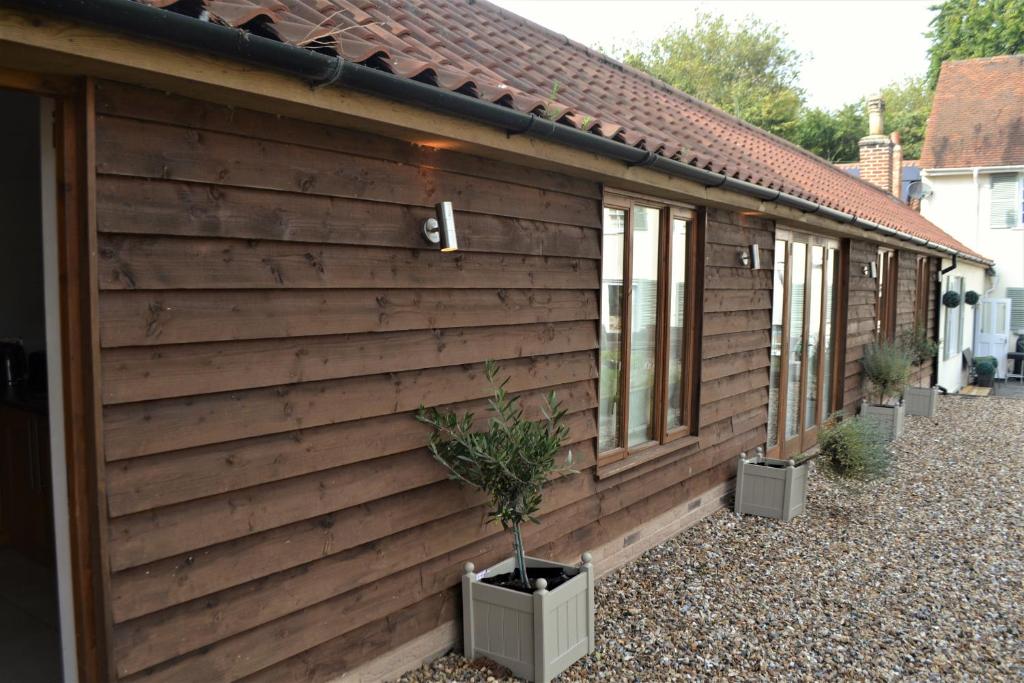 uma casa com uma parede de madeira com um vaso de plantas em Appletree Cottages em Mildenhall