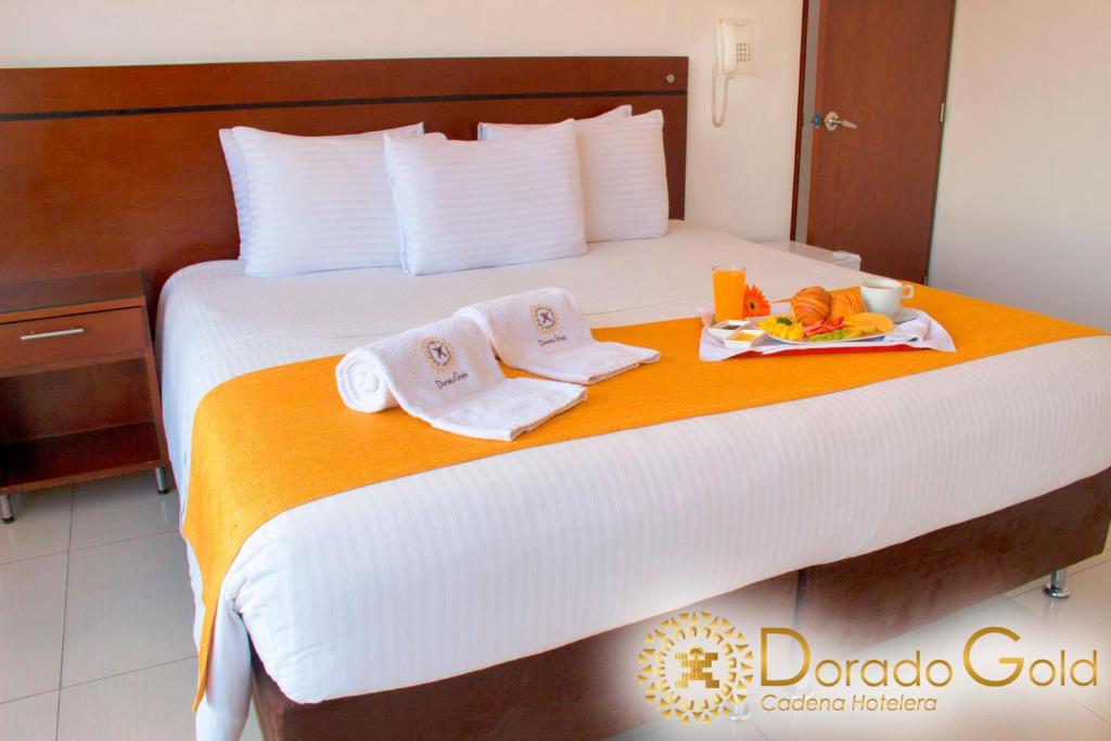Una cama con dos toallas y una bandeja de comida. en Hotel Dorado Gold en Bogotá
