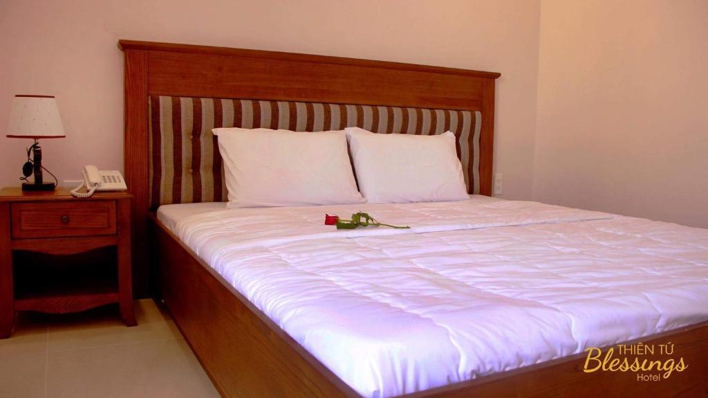 un letto con testiera in legno e telecomando di Thien Tu Hotel ad Ho Chi Minh