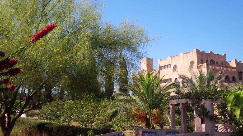 un jardin avec des arbres et un bâtiment en arrière-plan dans l'établissement Villa du Souss, à Agadir