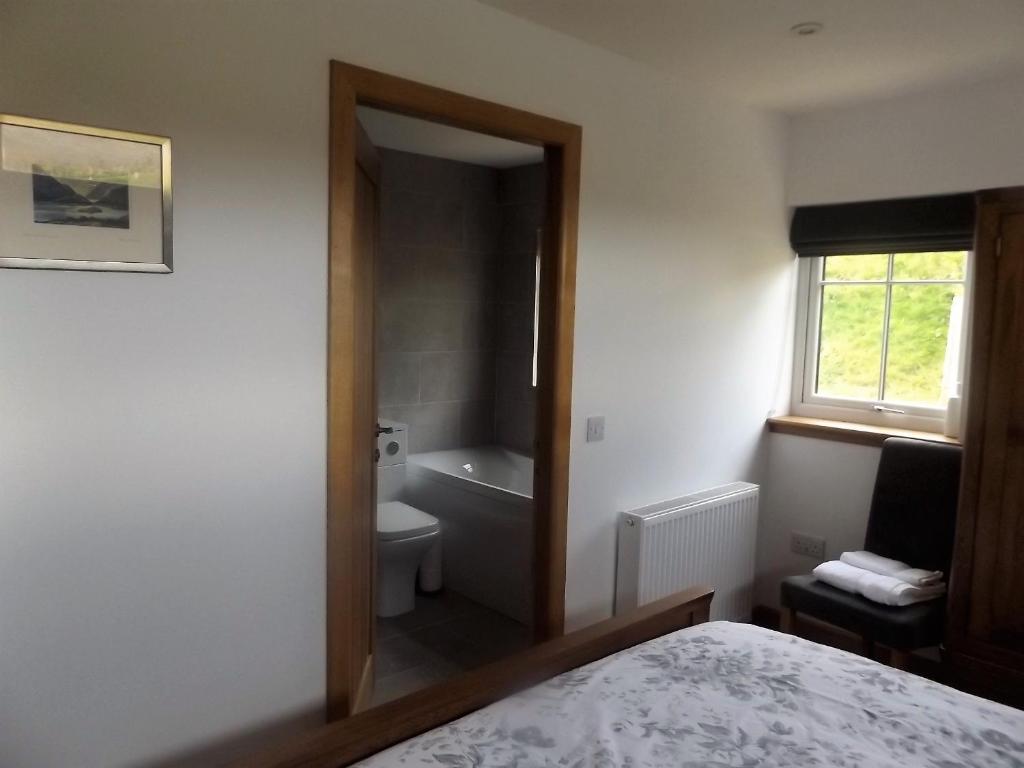 baño con cama, aseo y ventana en Keistle Cottage en Eyre