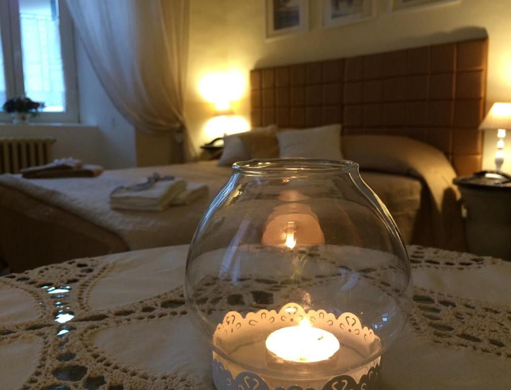 una candela in un vasetto di vetro su un tavolo in una camera da letto di Ad Palatium a Cori