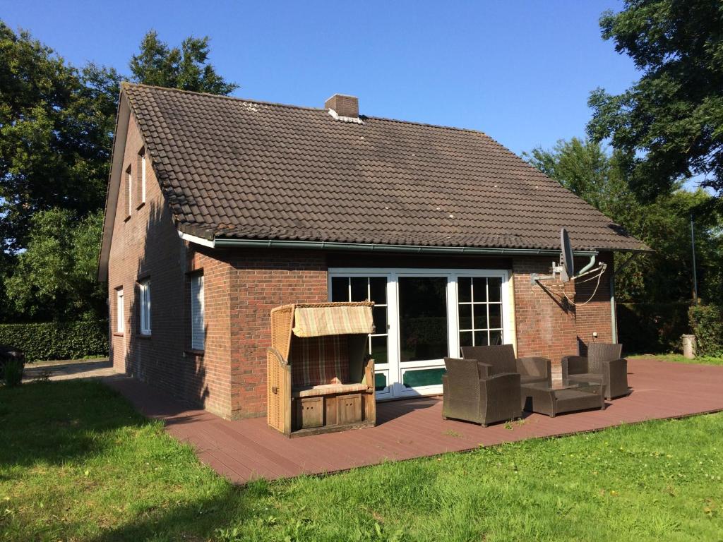 ein kleines Backsteinhaus mit einer Terrasse und 2 Stühlen in der Unterkunft Nordseehaus Anna in Neuharlingersiel