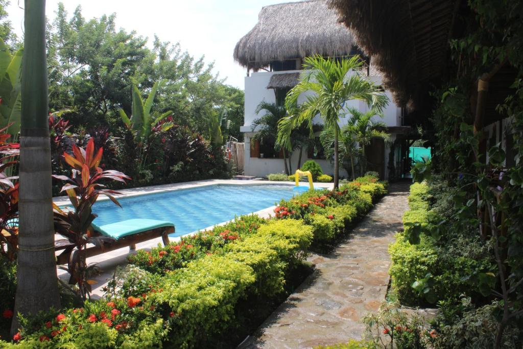 einen Pool in einem Resort mit einer Bank und Blumen in der Unterkunft Primaluna Beach Hostel in Palomino