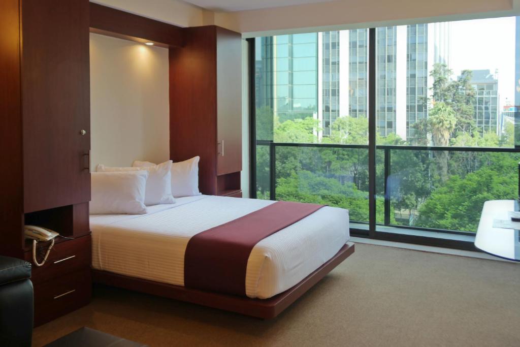 a hotel room with a bed and a large window at Suites Capri Reforma Ángel 380 in Mexico City