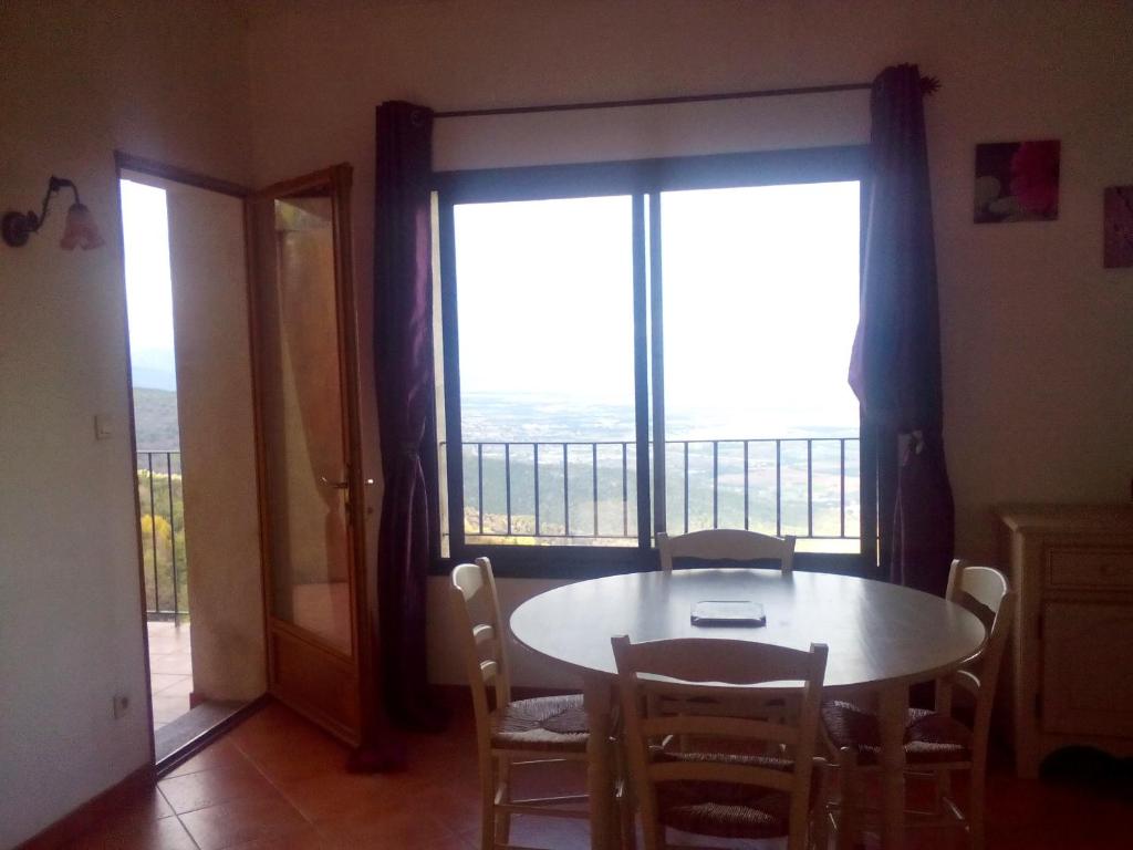 a dining room with a table and a large window at Gîte La Fontaine Corse in Loreto-di-Casinca