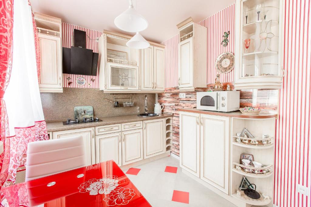 a kitchen with white cabinets and a red table at Apartment Haradsky Val 9 in Minsk