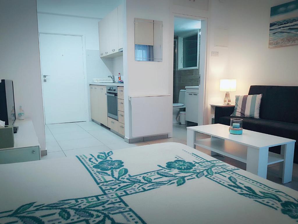 a white living room with a kitchen and a table at Billis Beach Apartment in Limassol