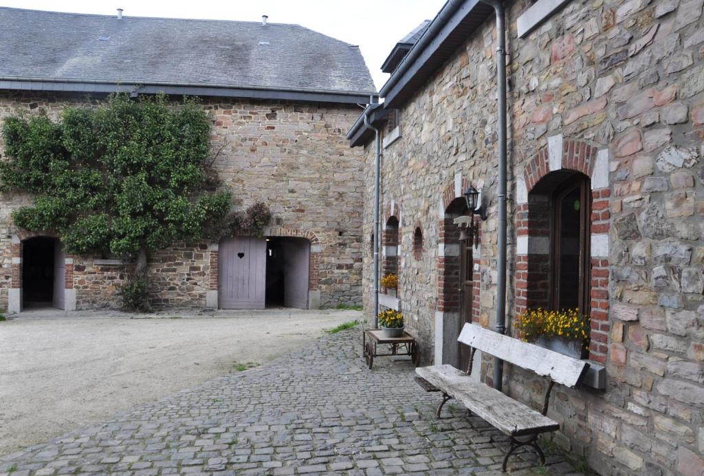 a bench sitting outside of a brick building at Gîte Ferme d'Ortie in Sainte-Ode