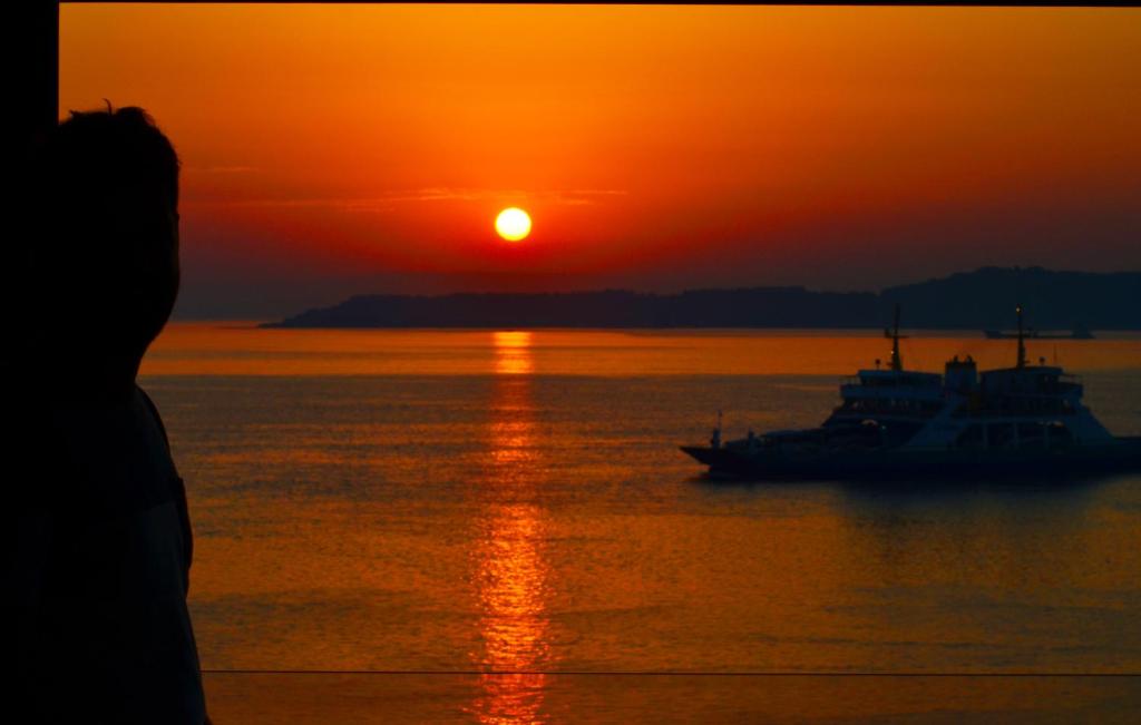 a boat in the water with a sunset at Hotel Deniz in Eceabat