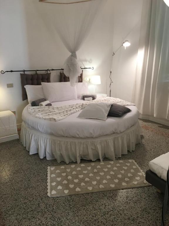 um quarto com uma cama grande e lençóis brancos em B&B Cristina e Stefano em Pisa