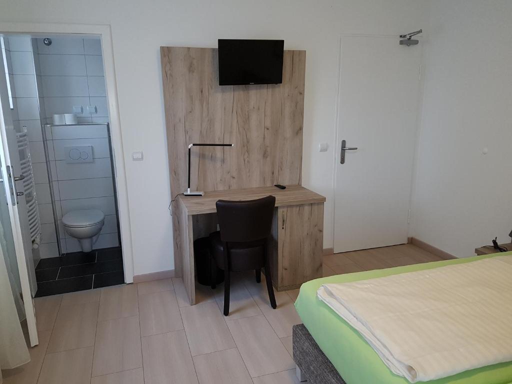 a bedroom with a desk with a television and a bed at Hotel Soad in Salach