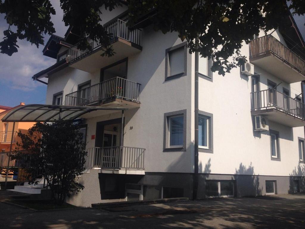 a white building with balconies on the side of it at Guest House Business in Valpovo