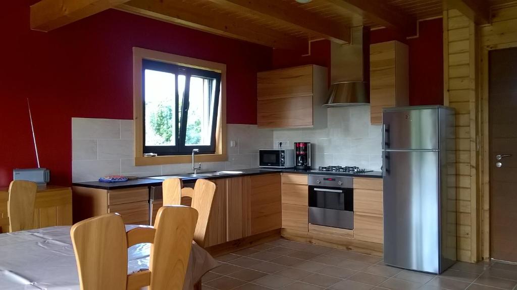 a kitchen with wooden cabinets and a table and a refrigerator at Entre Paimpol et Bréhat ! in Ploubazlanec