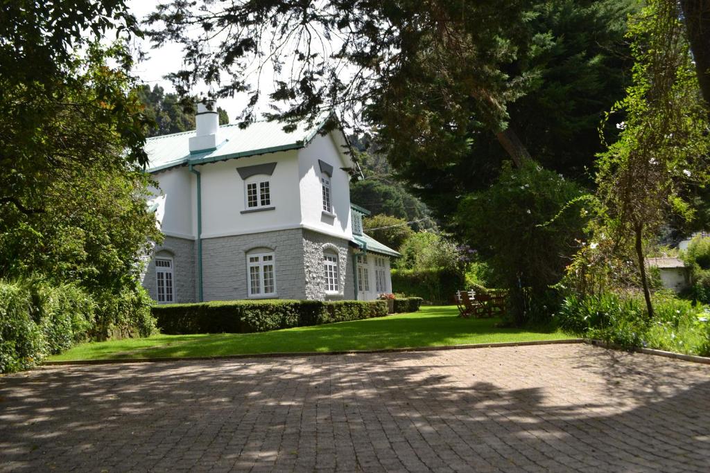 uma grande casa branca com uma entrada em Brockenhurst Bungalow em Nuwara Eliya