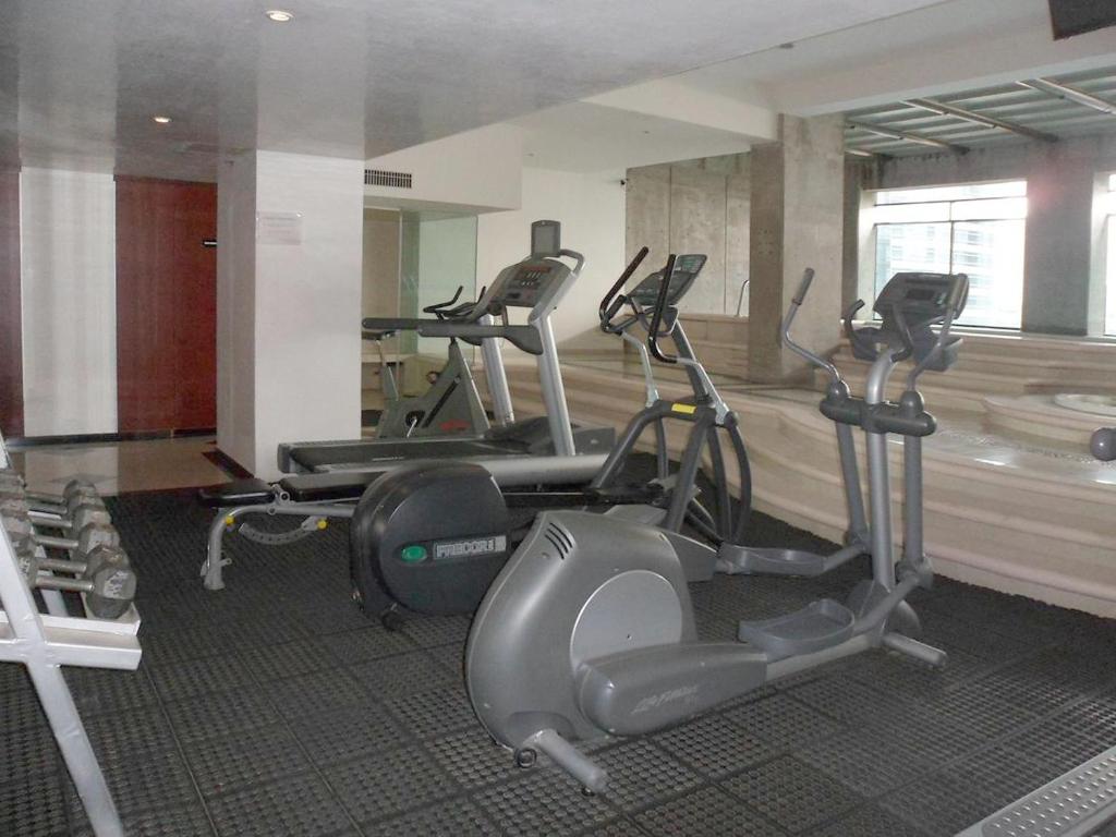 A mirrored fitness room contains cardio machines and a small dumbbell area.
