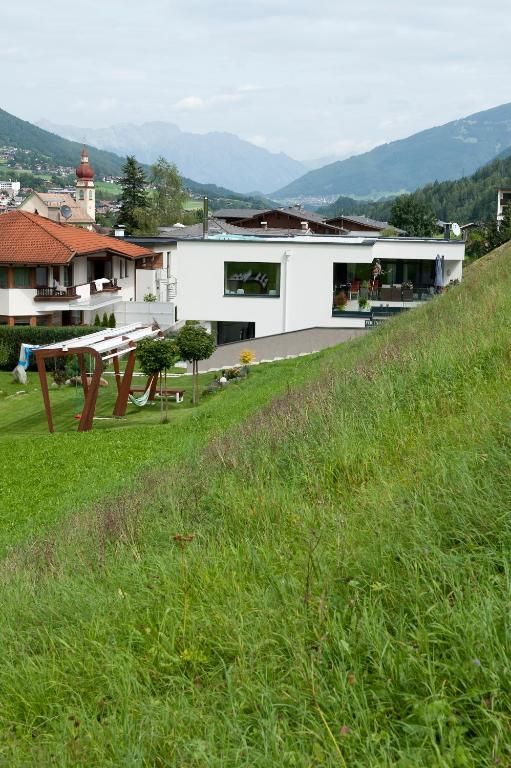 a white building with a picnic table in a field at Ferienwohnung Robi in Fulpmes