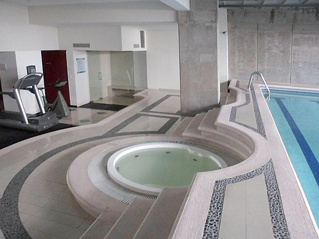 A round hot tub sits beside the indoor pool and exercise equipment.