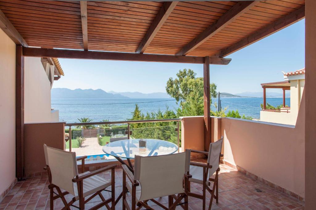 patio ze stołem i krzesłami oraz widokiem na ocean w obiekcie Aegina Villa Kalliopi w mieście Egina