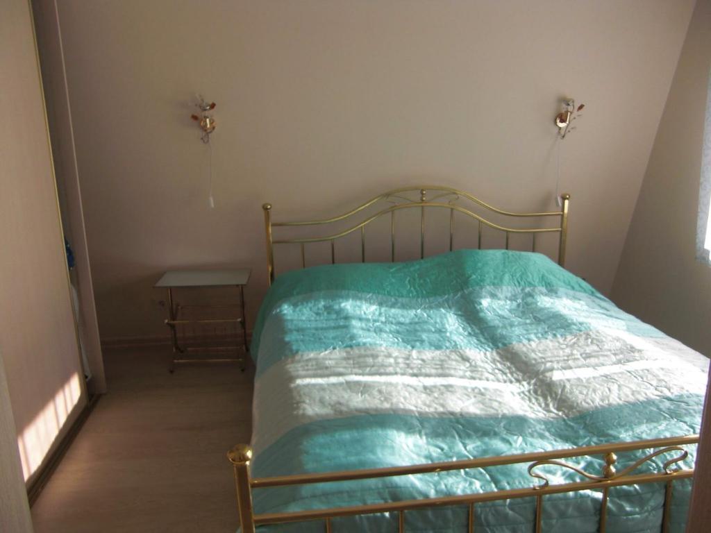 a bed with a green comforter in a room at Butas Prie Nemuno in Druskininkai