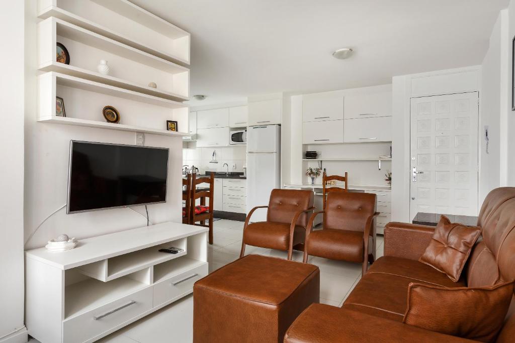 sala de estar con TV de pantalla plana y sillas marrones en Apto 2 quartos, 1 quadra do Mar/Shop. Atlantico, en Balneário Camboriú