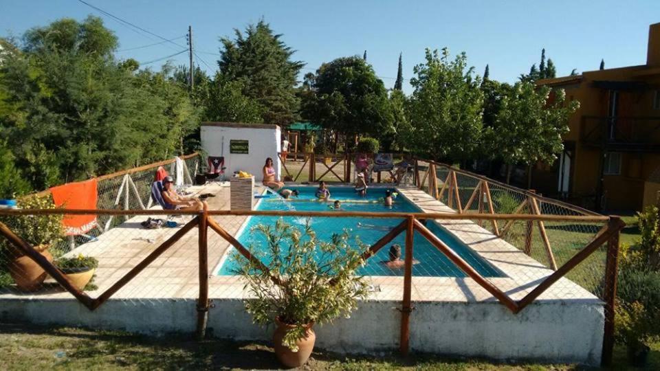a swimming pool with people sitting around it at Cabañas Esferas de Cristal in Capilla del Monte