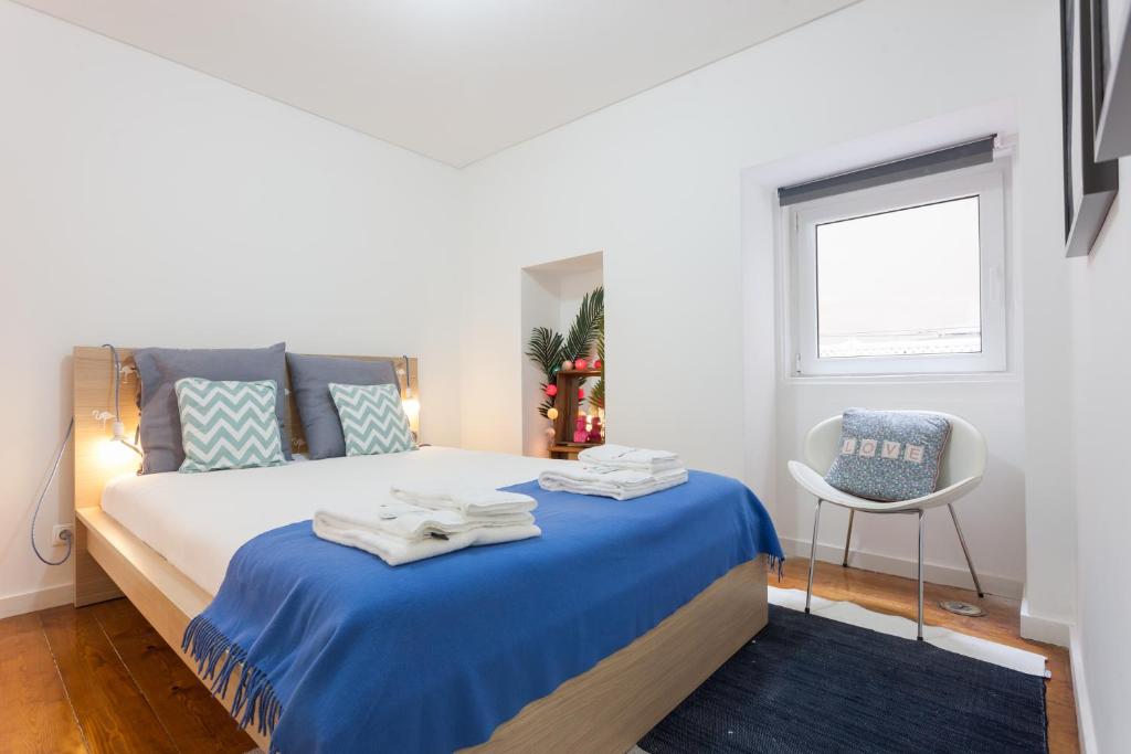 um quarto com uma cama com lençóis azuis e uma cadeira em FLH Príncipe Real Comfortable Flat em Lisboa