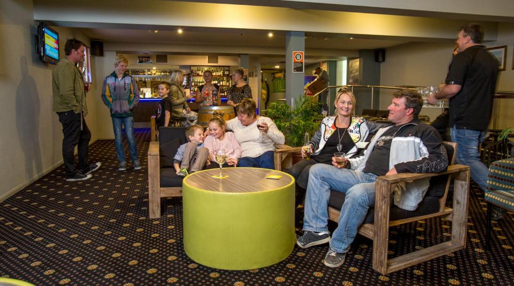 a family sitting around a table in a room at Laurieton Hotel in Laurieton