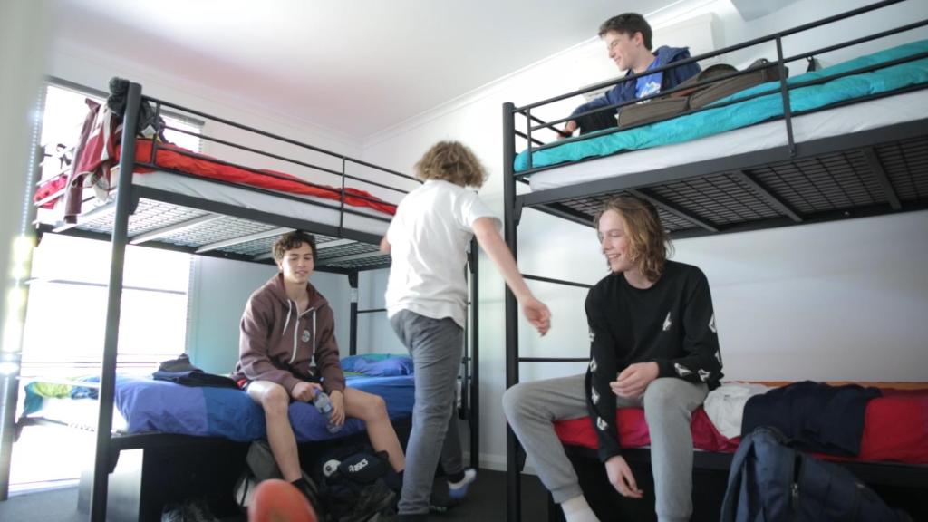 three people sitting on bunk beds in a dorm room at Alpine Sports Lodge in Bright