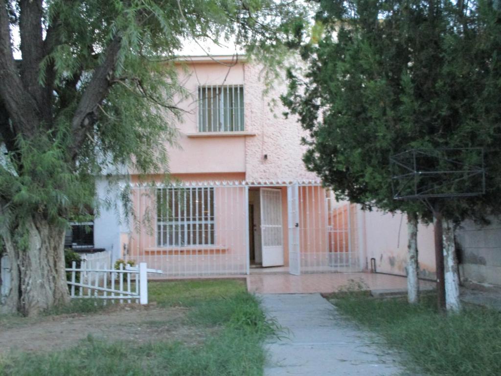 Uma casa cor-de-rosa com uma cerca branca à frente. em Apartment Blanquita Consulado Cedros em Ciudad Juárez