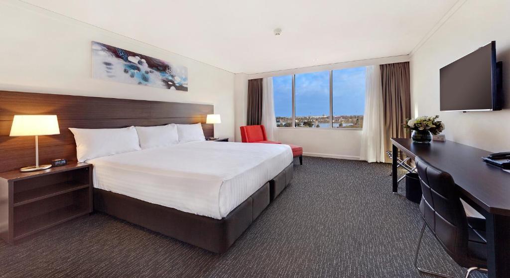 メルボルンにあるベイビュー エデン メルボルンのベッドとデスクが備わるホテルルームです。