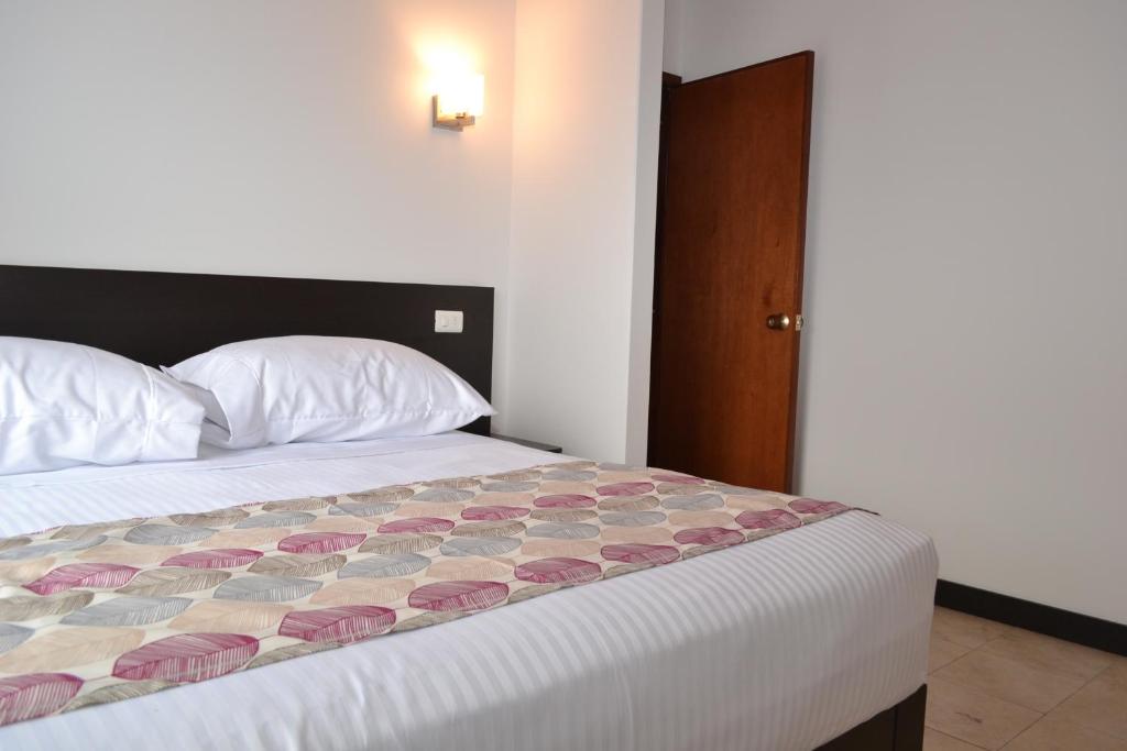 ein Schlafzimmer mit einem Bett mit einer Decke darauf in der Unterkunft Apartahotel Doble3 in Paipa