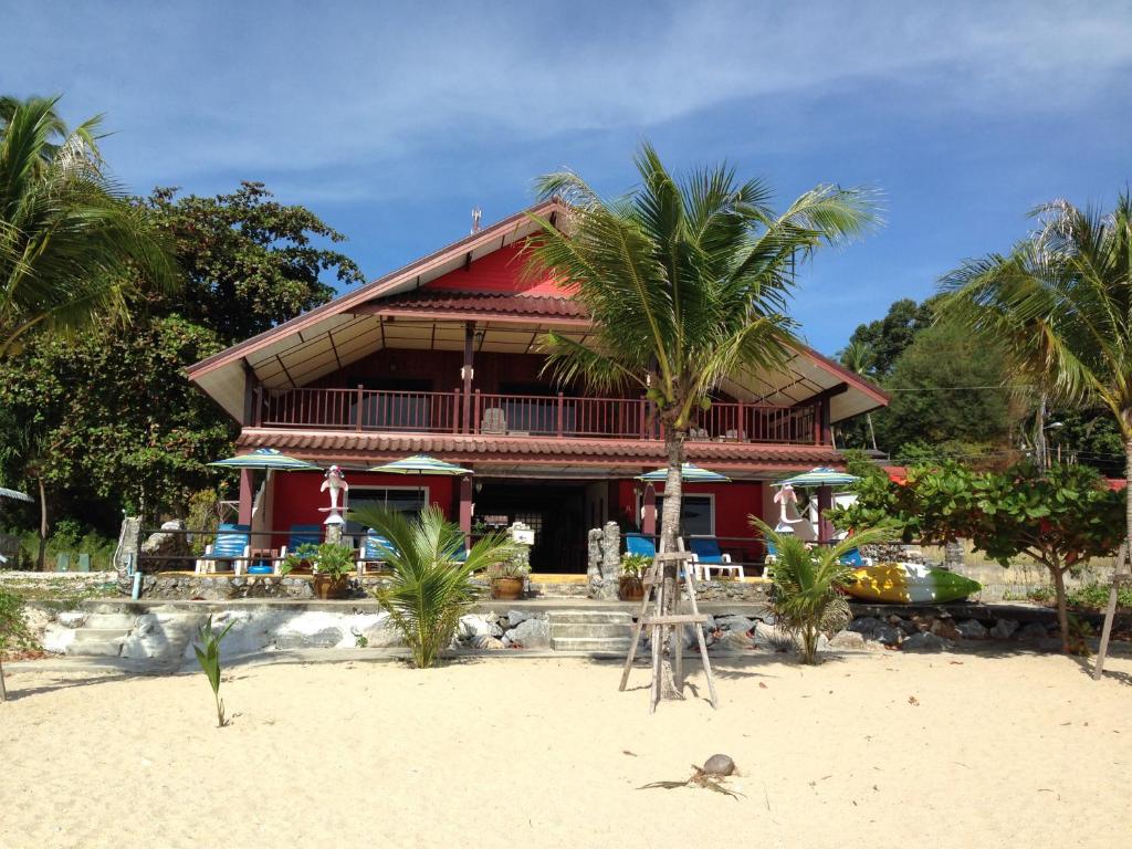 a red house on the beach with palm trees at Sea Breeze House, Naiplao Beach in Khanom