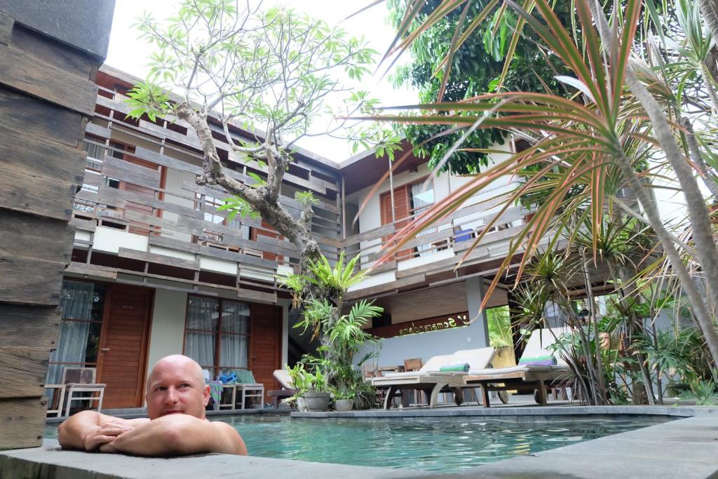 a man laying in a swimming pool in front of a building at Semarandana Bedrooms and Pool in Sanur