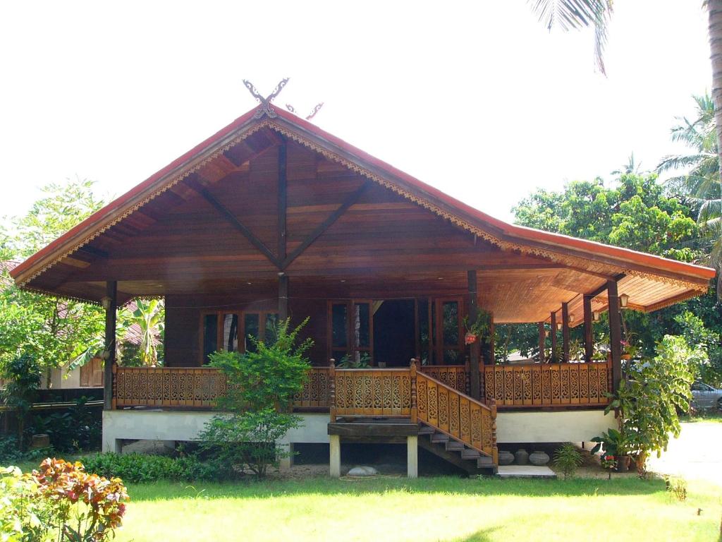 Tamarind Lodge في شاطئ مينام: منزل صغير مع شرفة خشبية كبيرة
