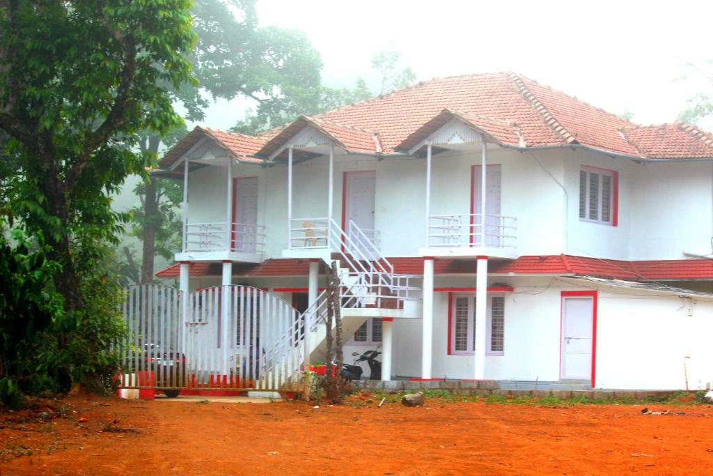 a white house with red trim and a fence at Vacanza Estate House in Kakkabe