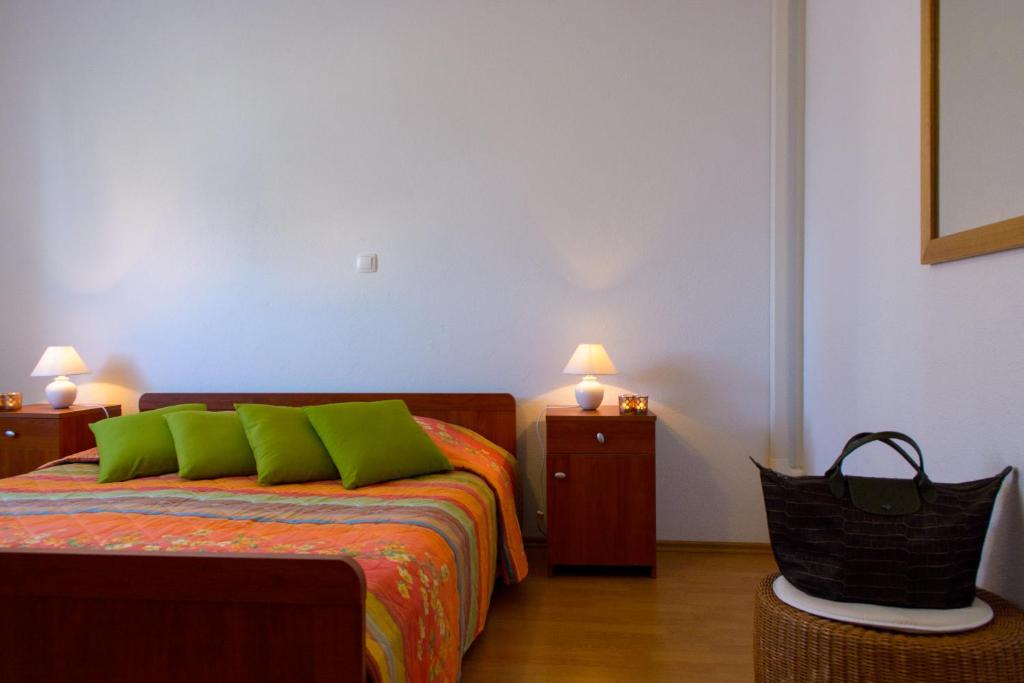 a bedroom with a bed with green pillows and a chair at Apartments Topli Bok in Trogir