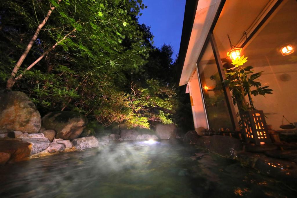 a house with a stream of water in front of a house at Sanseikan in Noboribetsu