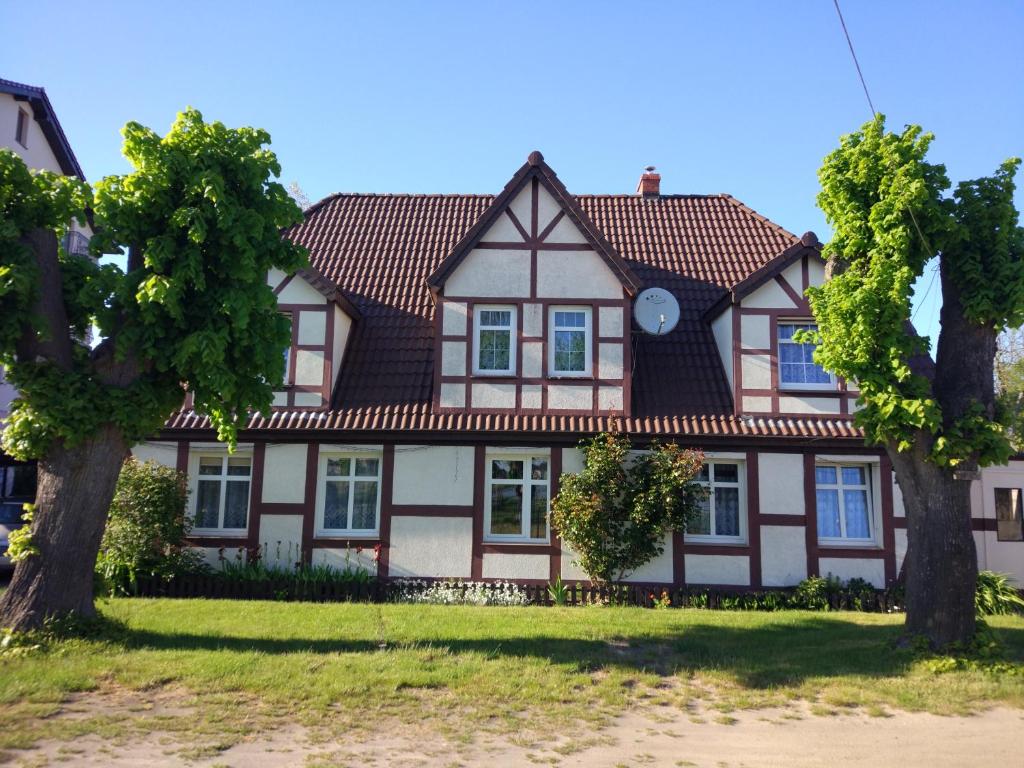 une maison avec un toit carrelé et deux arbres dans l'établissement Pokoje w Mielnie, à Mielno