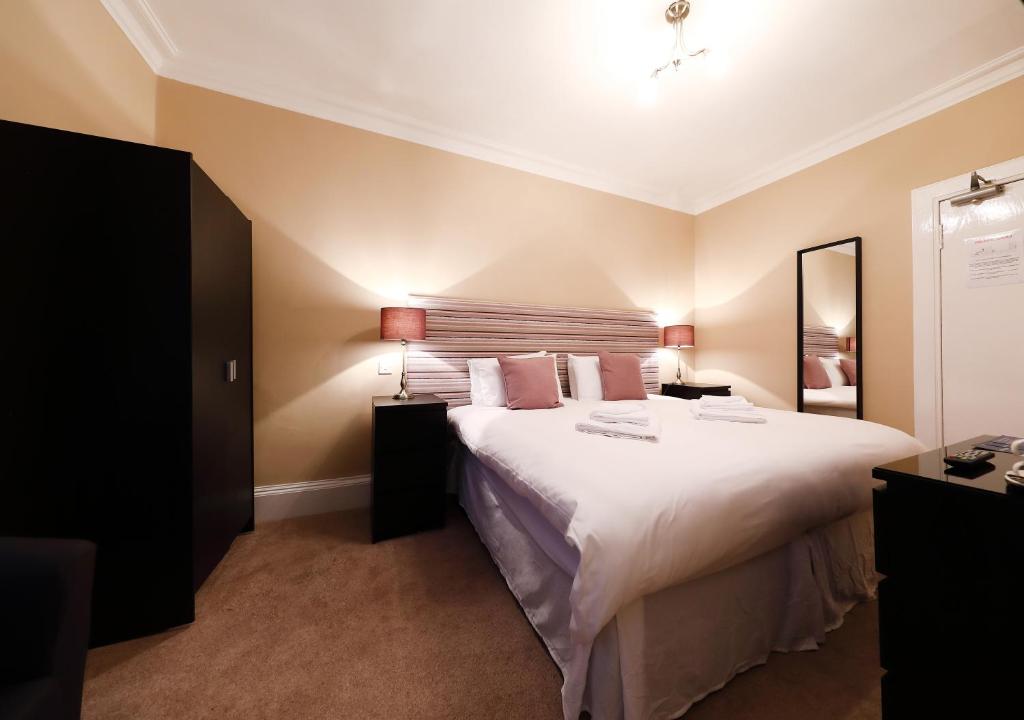 a bedroom with a large bed with white sheets and pillows at The Station Hotel in Carnoustie